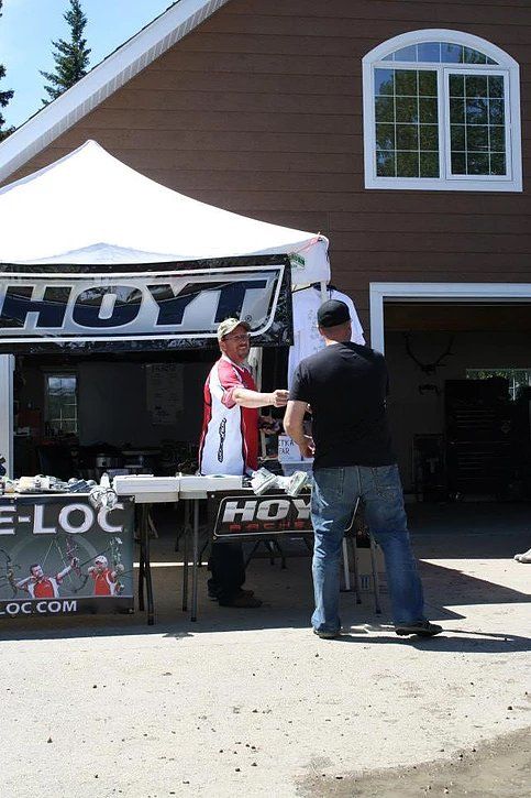 Two men shaking hands in front of a hayt tent