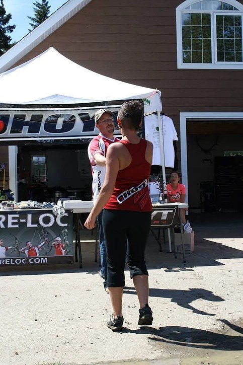 A woman in a red tank top is standing in front of a sign that says hoy