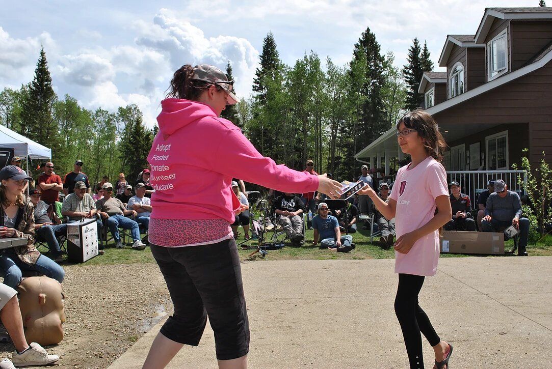 A woman in a pink hoodie is dancing with a little girl in a pink shirt