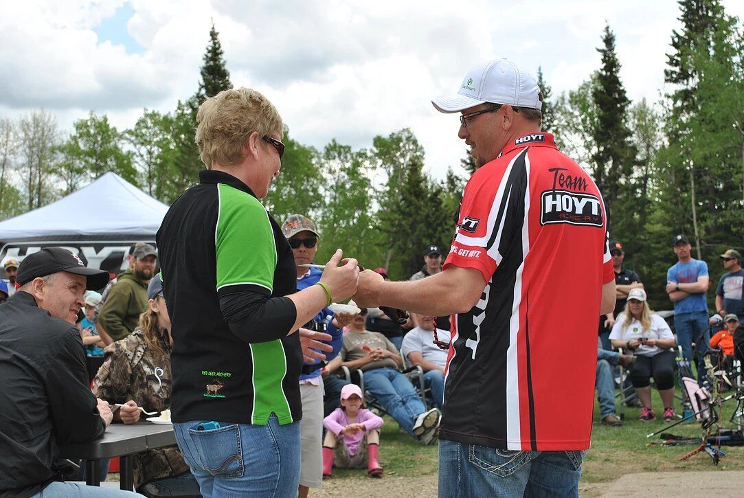 A man in a red and black shirt with the word hmv on the back shakes hands with a woman in a green shirt