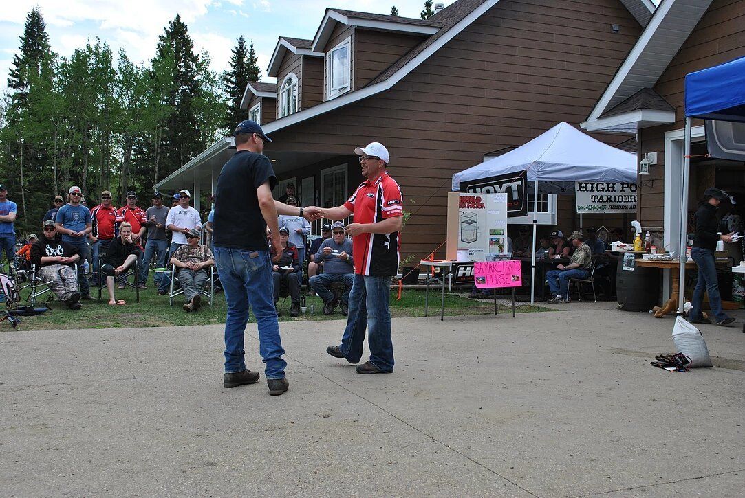 Two men are shaking hands in front of a crowd of people