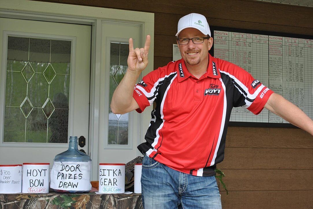 A man in a red shirt is giving a horn sign