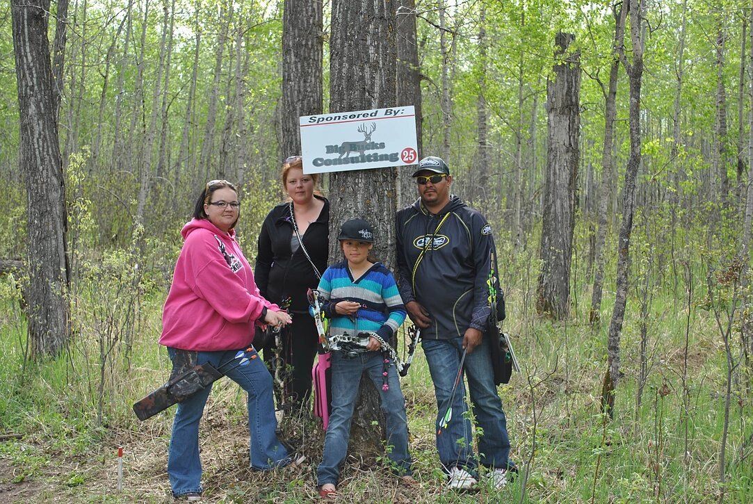 A group of people standing next to a tree in the woods.