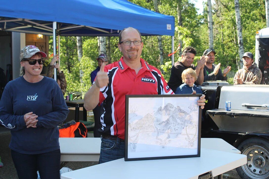A man in a red shirt is holding a framed picture.