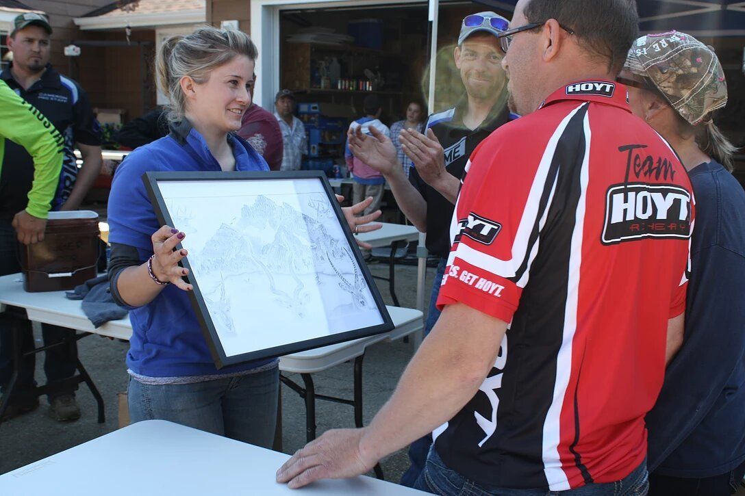 A man in a hoyt shirt holds a framed map