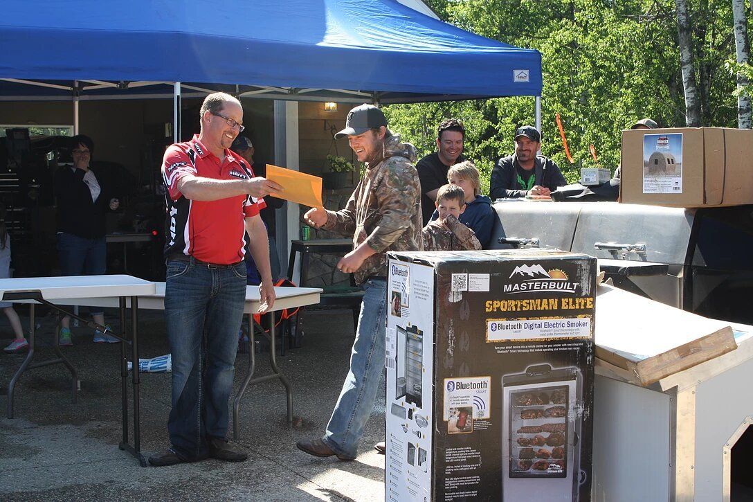 A man in a red shirt is giving a prize to another man