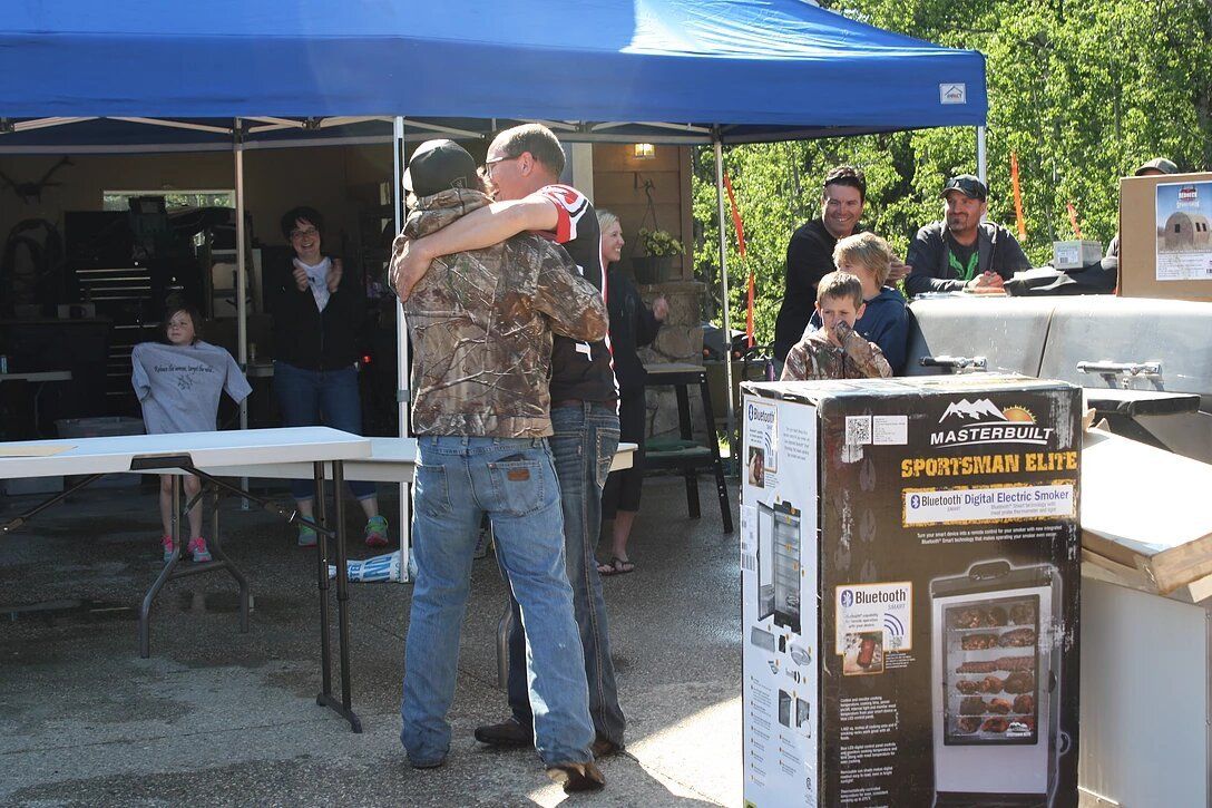 A man in a camo shirt is hugging another man