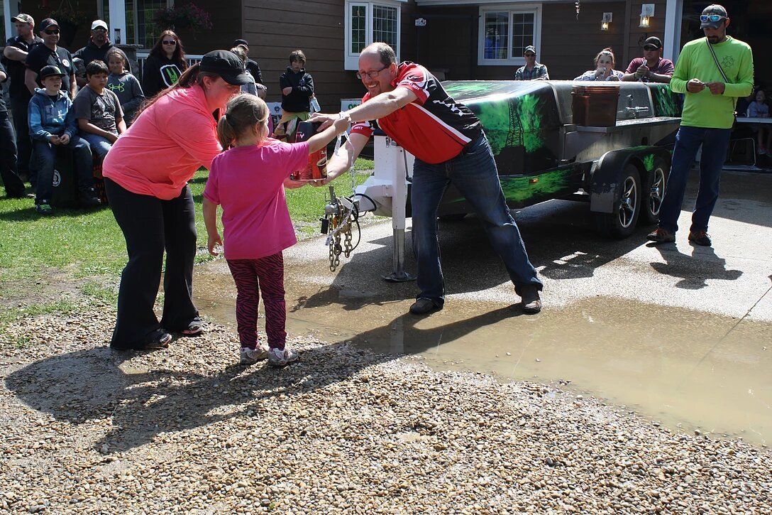 A man and a little girl are playing in a muddy puddle.