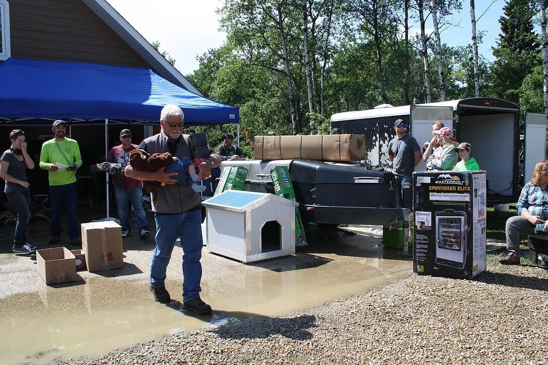 A man is holding a dog in front of a dog house