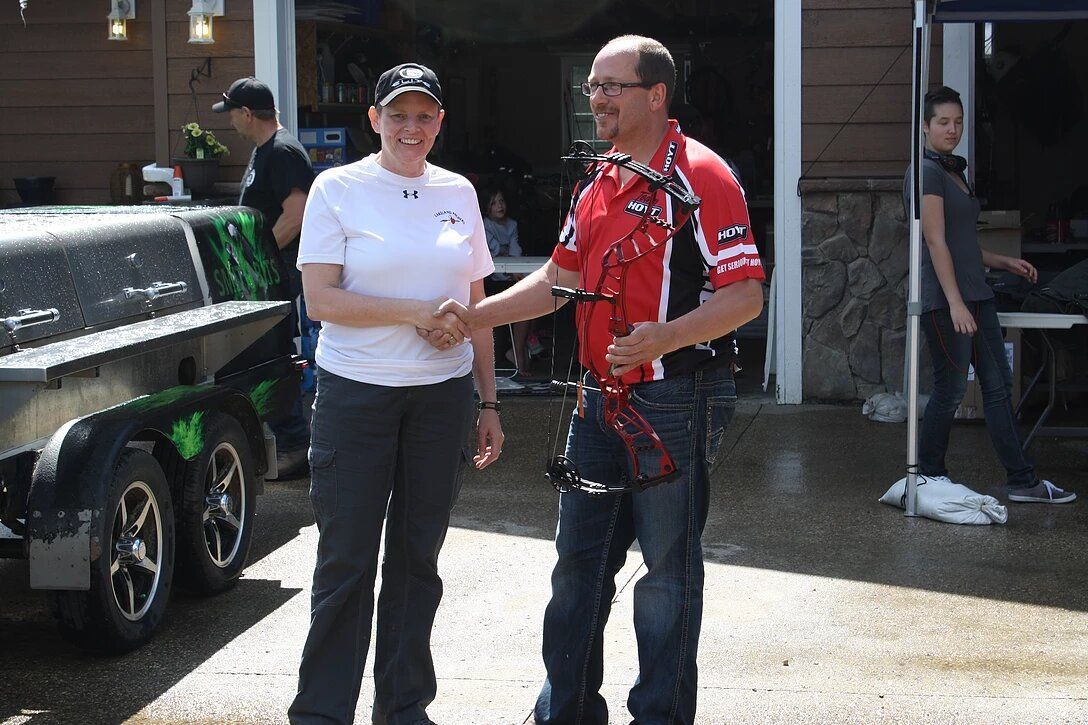 A man and a woman are shaking hands in front of a trailer.