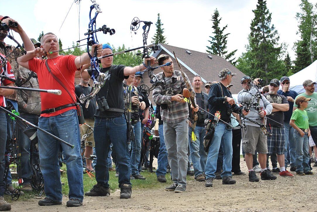 A group of people are standing in a field holding bows and arrows.