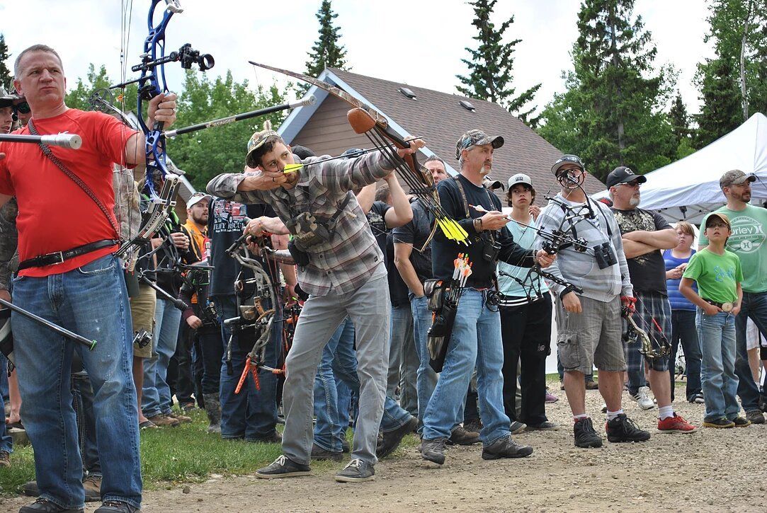 A group of people are standing in front of a building holding bows and arrows.