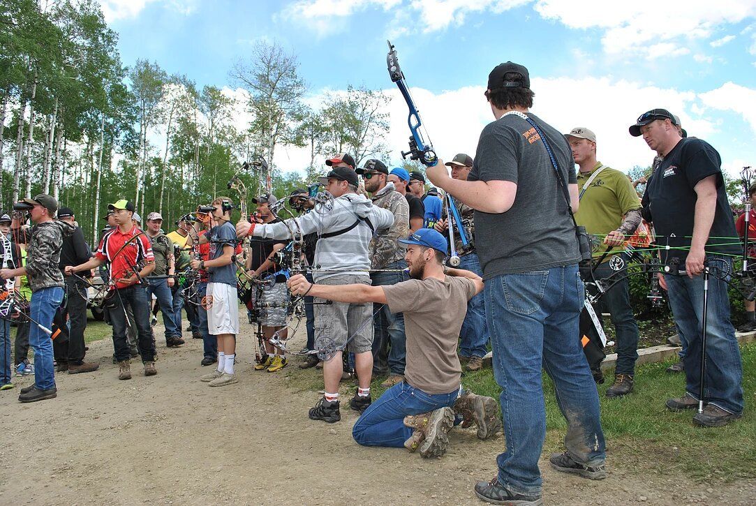 A man is kneeling down in front of a group of people holding bows and arrows.