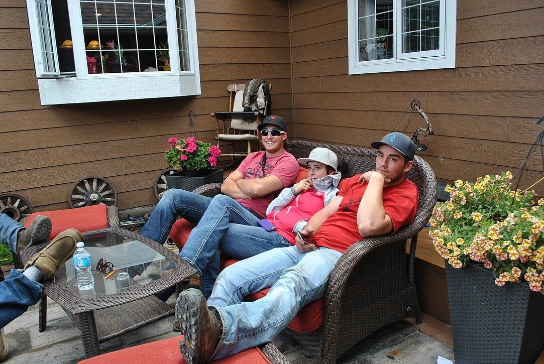 A group of people are sitting on a patio in front of a house.