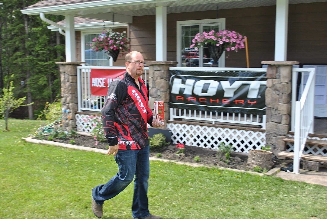 A man is walking in front of a house with a hoyt sign on the porch.