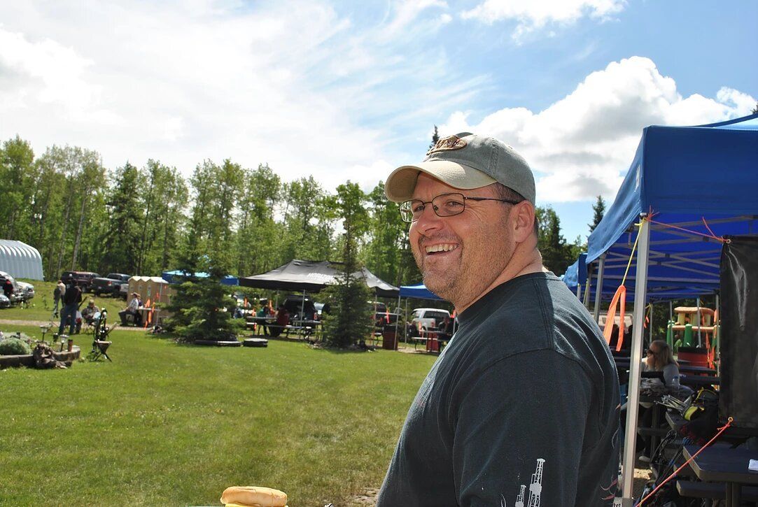 A man is standing in a field with a blue tent in the background.