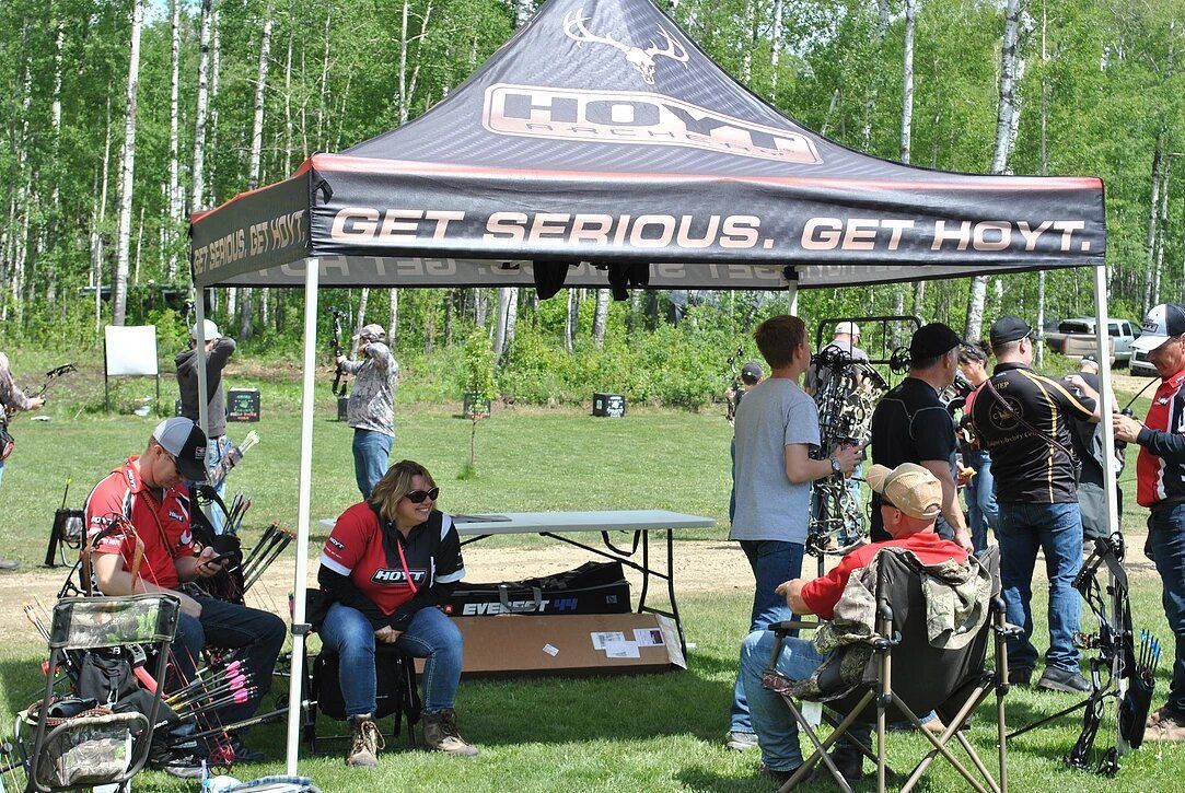 A group of people are gathered under a tent that says get serious get hunt.