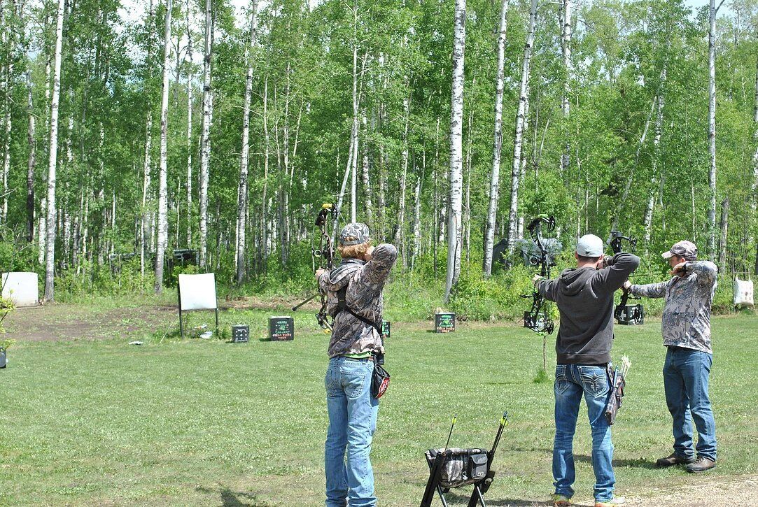 A group of people are standing in a field holding bows and arrows.
