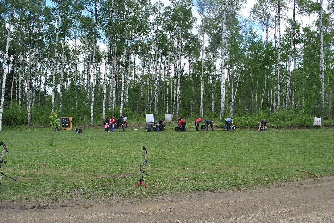 A group of people are sitting in a field with trees in the background.