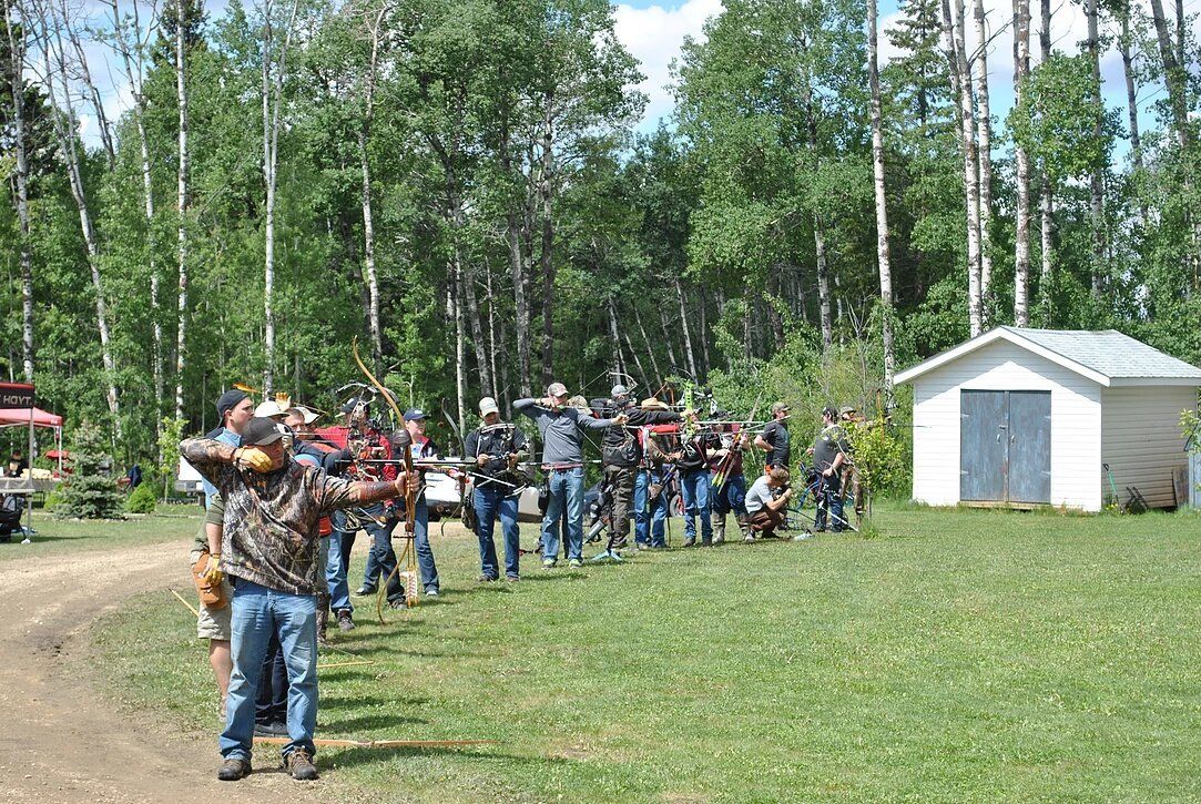 A group of people are standing in a field holding bows and arrows.