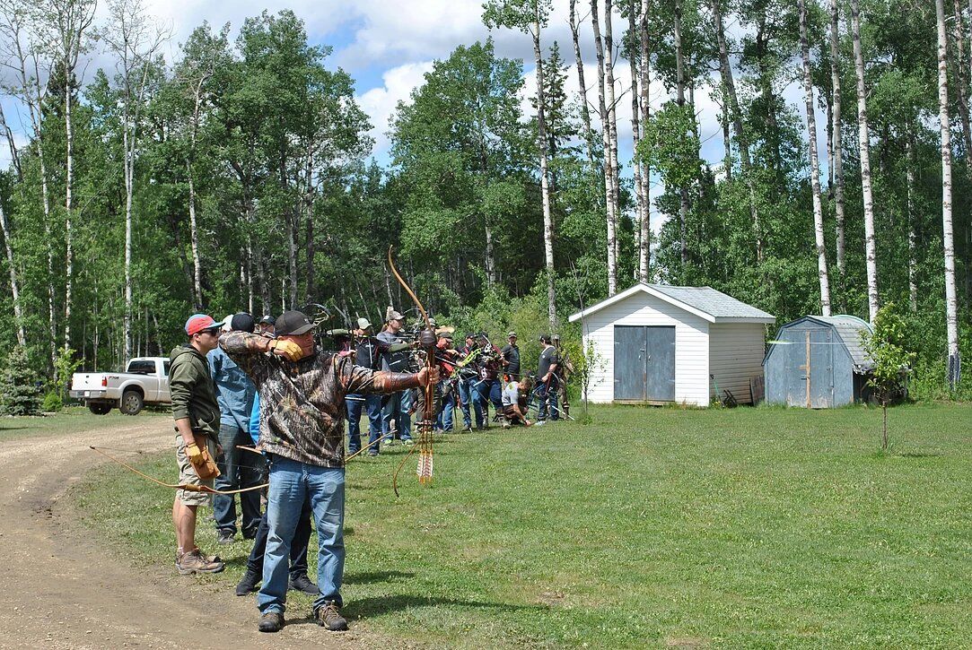 A group of people are standing in a field with a shed in the background.