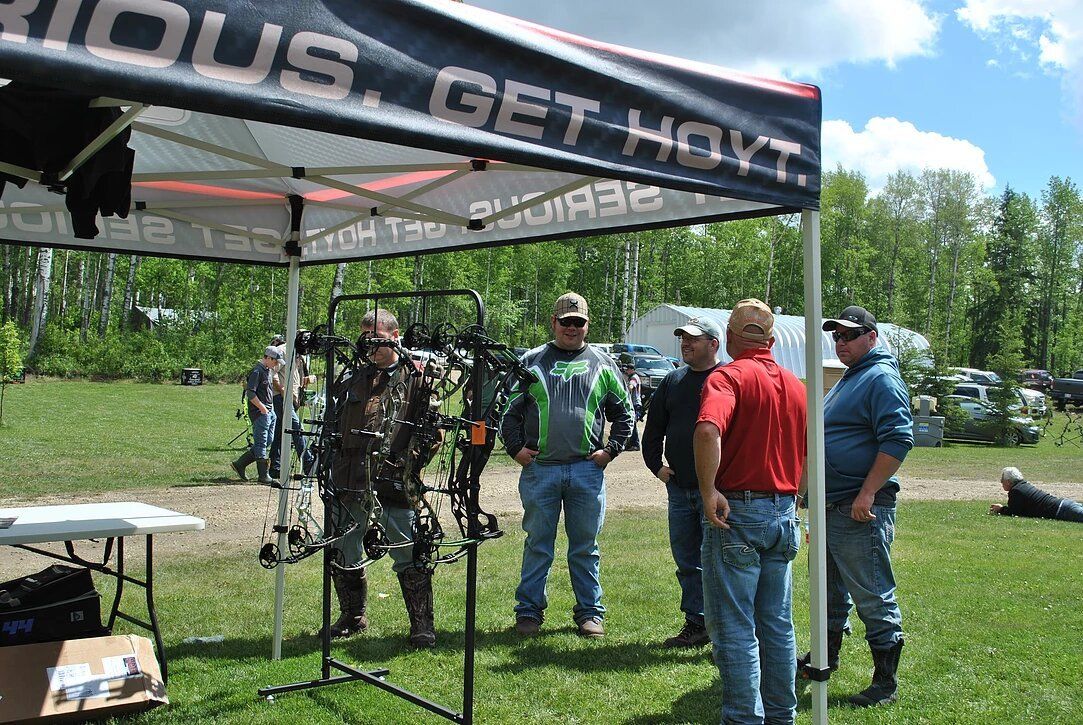 A group of men are standing under a tent that says get hot