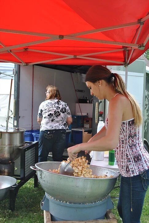 A woman is preparing food in a large bowl under a red tent.