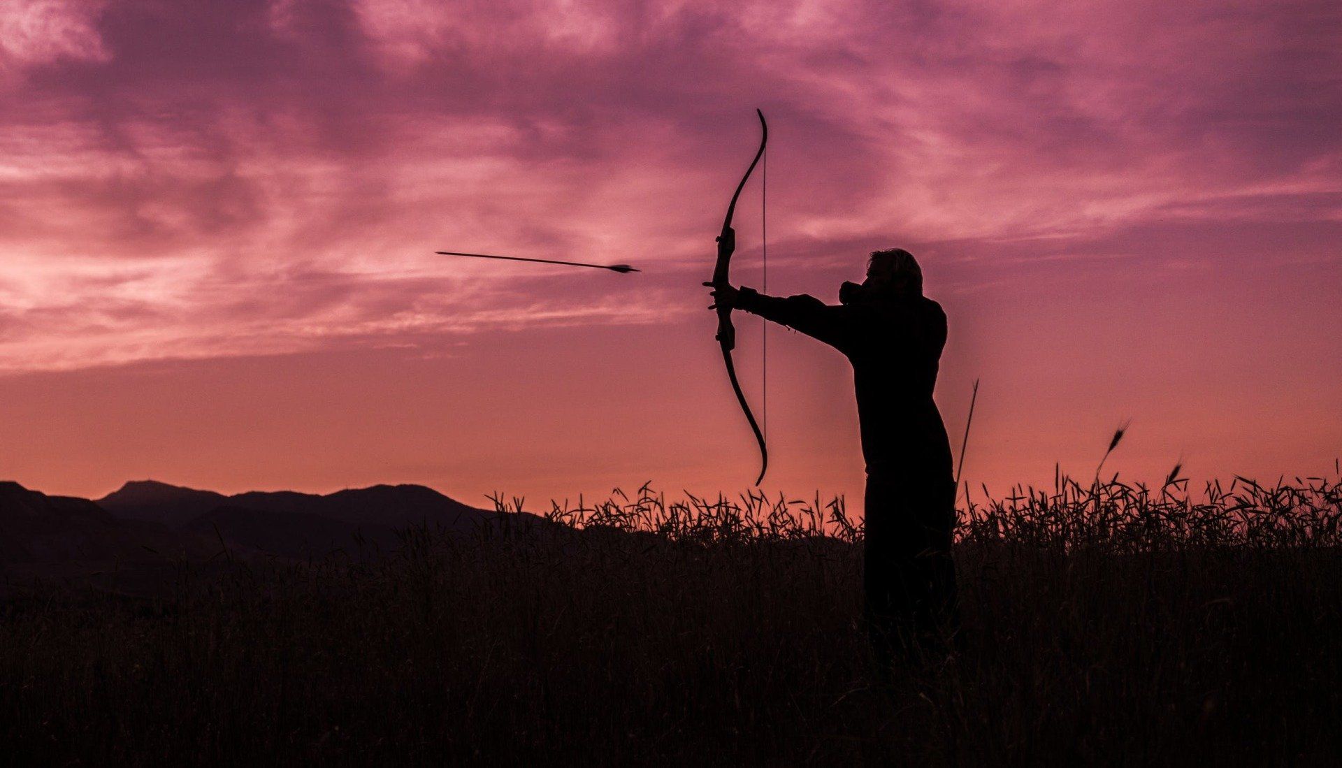 Archery shooting an arrow at a field target.