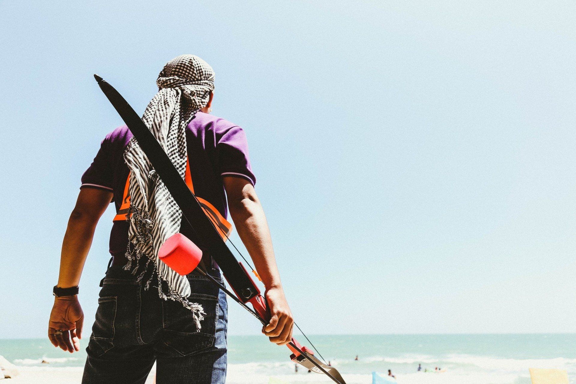 A man is standing on a beach holding a fishing rod.
