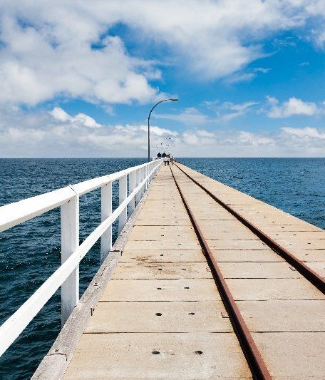 A pier going into the ocean with a white railing | Geographe Bay Holiday Park in Busselton