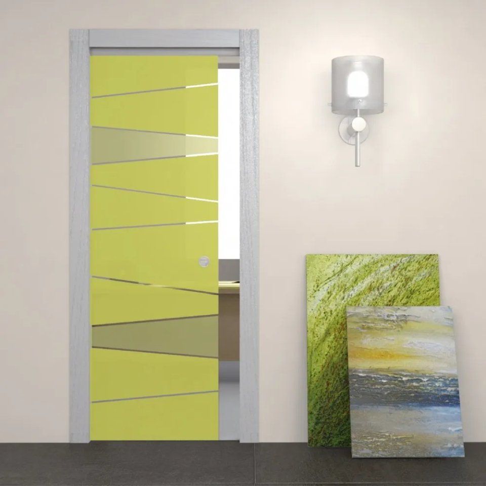 Interno moderno con porta in vetro smerigliato verde lime, applique a muro e quadri astratti appoggiati alla parete.