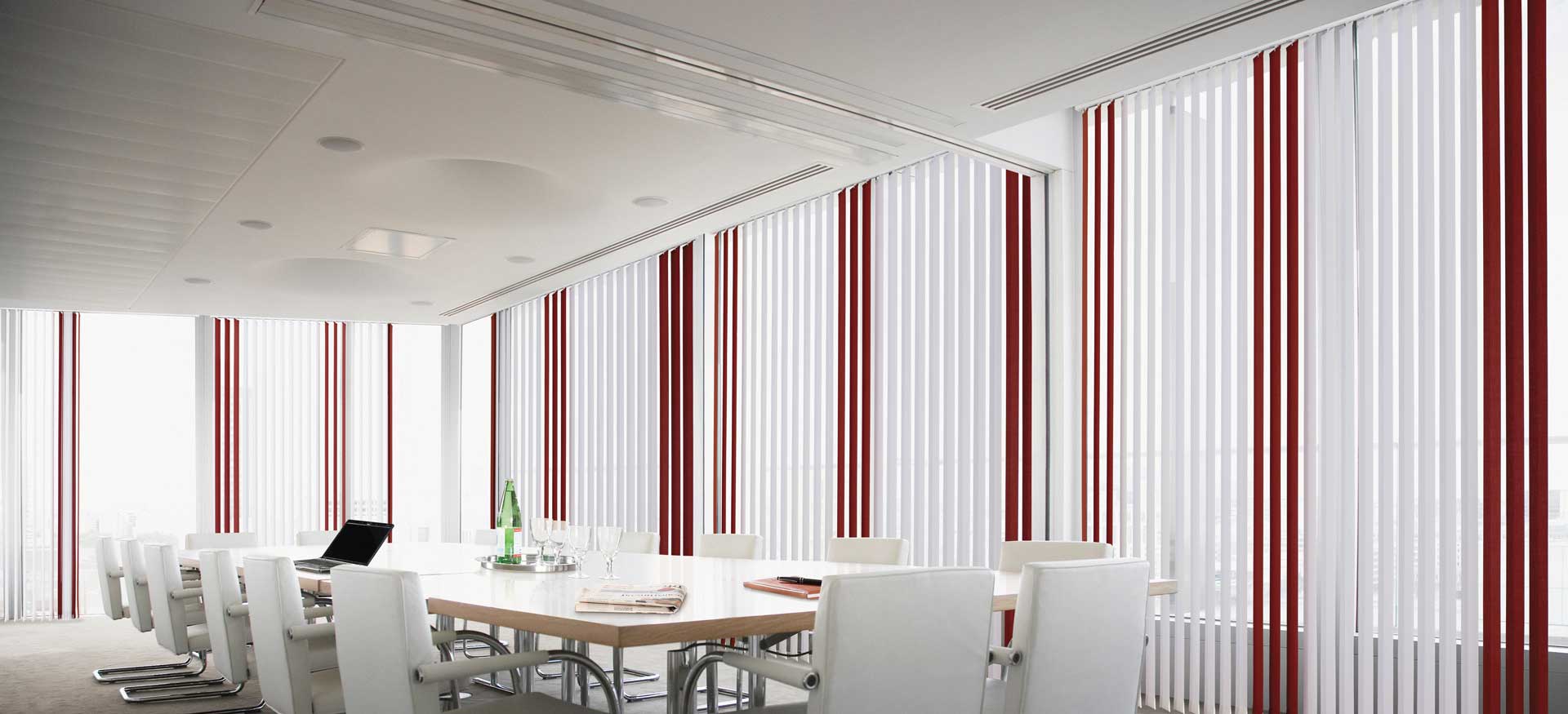 Sala da pranzo luminosa e moderna con lungo tavolo, sedie bianche e decorazioni murali a righe rosse.