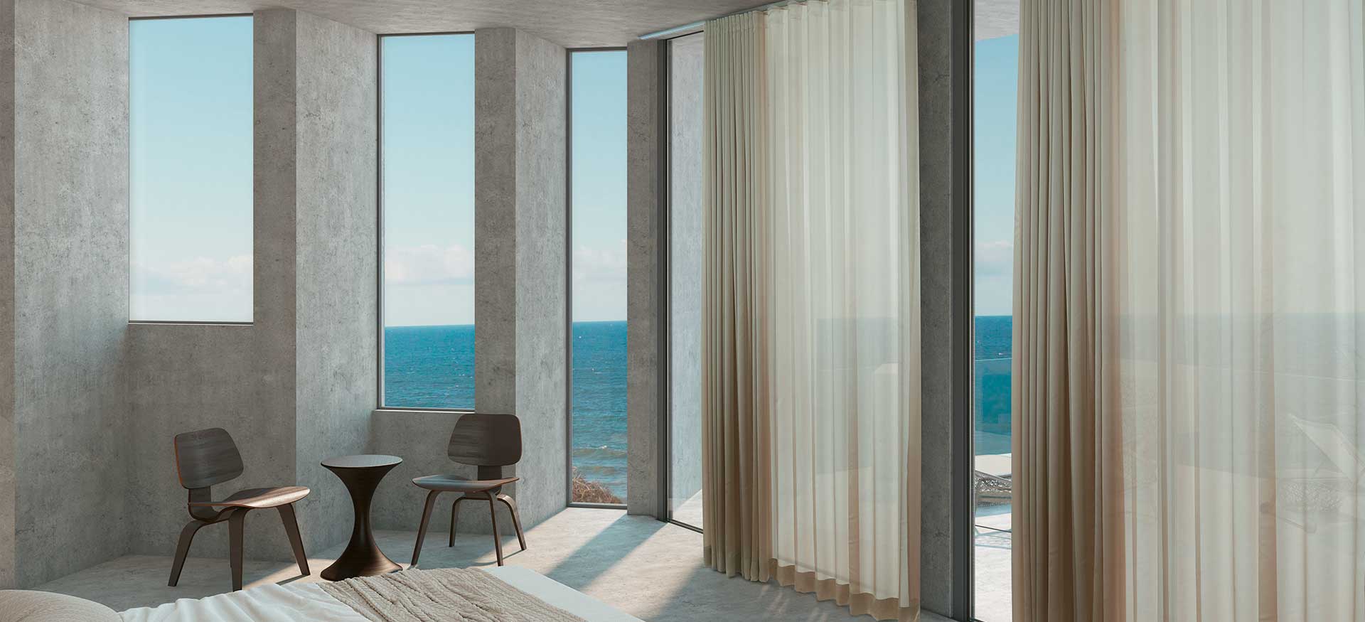 Camera moderna in riva al mare con ampie finestre, tende trasparenti e due sedie con vista sull'oceano.