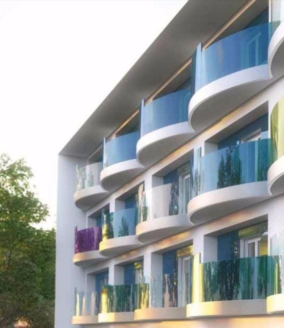 Moderno condominio con balconi curvi e ringhiere in vetro colorate.