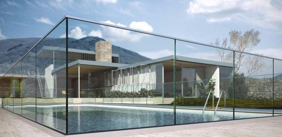 Casa moderna con piscina racchiusa da pareti in vetro, immersa in un paesaggio montuoso.