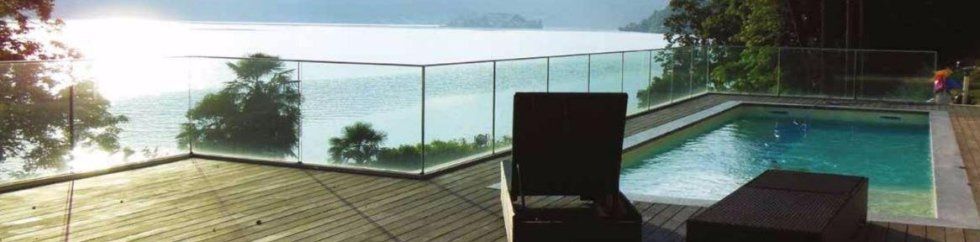 Terrazza con piscina vista oceano, dotata di lettini e una sedia nera con vista sul mare.