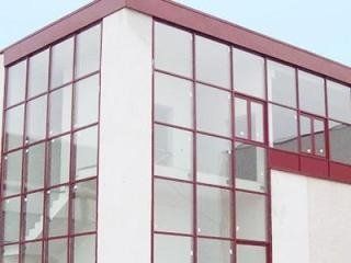 Angolo di un edificio moderno con finestre in vetro incorniciate di rosso e pareti bianche.
