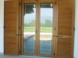 Doppie porte finestre in legno con persiane, che si aprono su una luminosa vista esterna.
