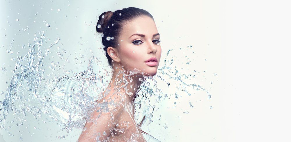 Eine Frau spritzt sich Wasser ins Gesicht.