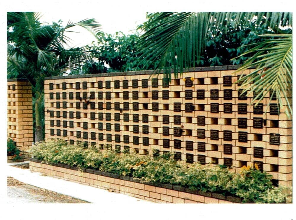 A Brick Wall Surrounded by Plants and Palm Trees — Northern Rivers Headstones in Casino, NSW