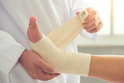 Ankle Sprains — Doctor Bandaging Woman's Ankle in Jackson, MI Ankle Sprains — Doctor Bandaging Woman's Ankle in Jackson, MI