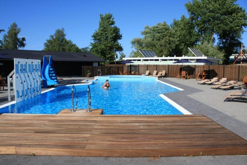Gæster bader og nyder solen ved swimmingpoolen.