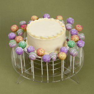 Cake on a stand surrounded by colorful cake pops.