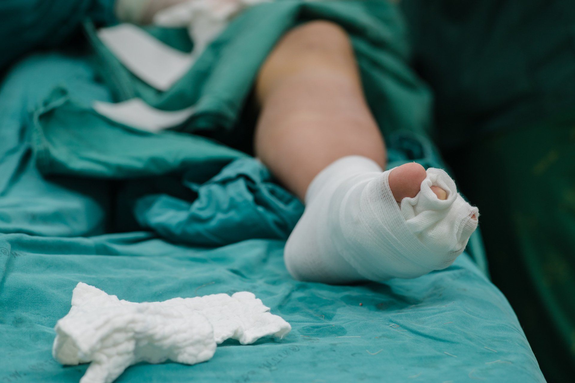 Wrapped foot on an operating table with a bloody bandage and gauze nearby