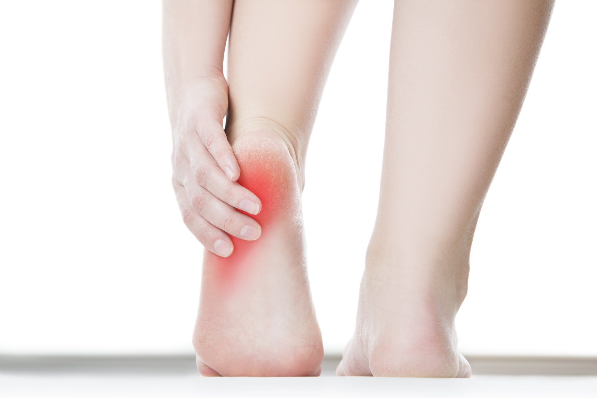 Person holding a painful red heel on a white background