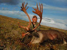 A man is standing next to a large deer in a field.