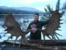 A man is holding a moose antlers in his hands in the snow.