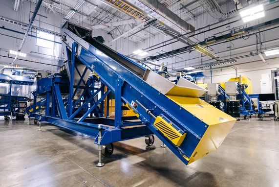 A blue and yellow conveyor belt is sitting in a warehouse.