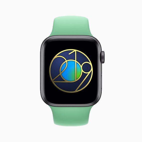 An apple watch with a green band and a gold circle on the screen