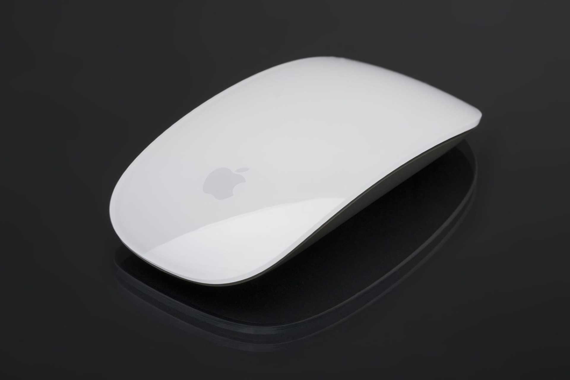 A white apple mouse is sitting on a black surface